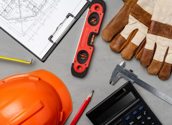 Architect tools sush as hardhat, blueprints and calculator top view